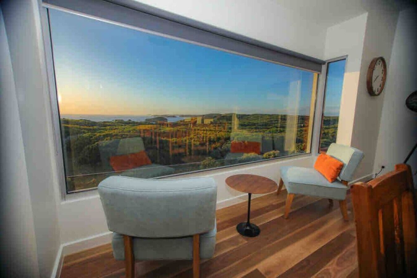 A room with a large window, two chairs, a small table, and a wooden floor.