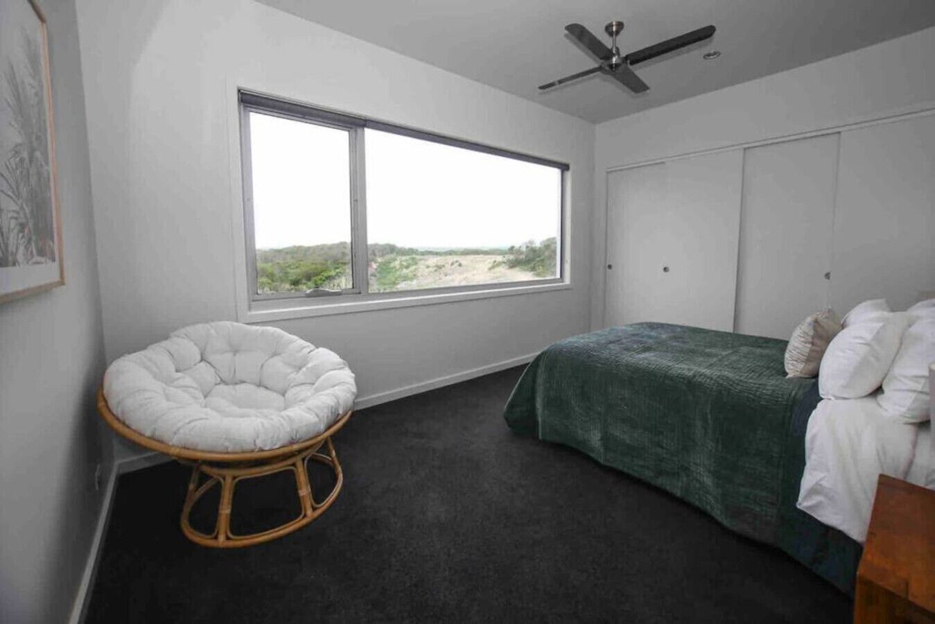 A bedroom with a bed, a chair, a window, and a ceiling fan.
