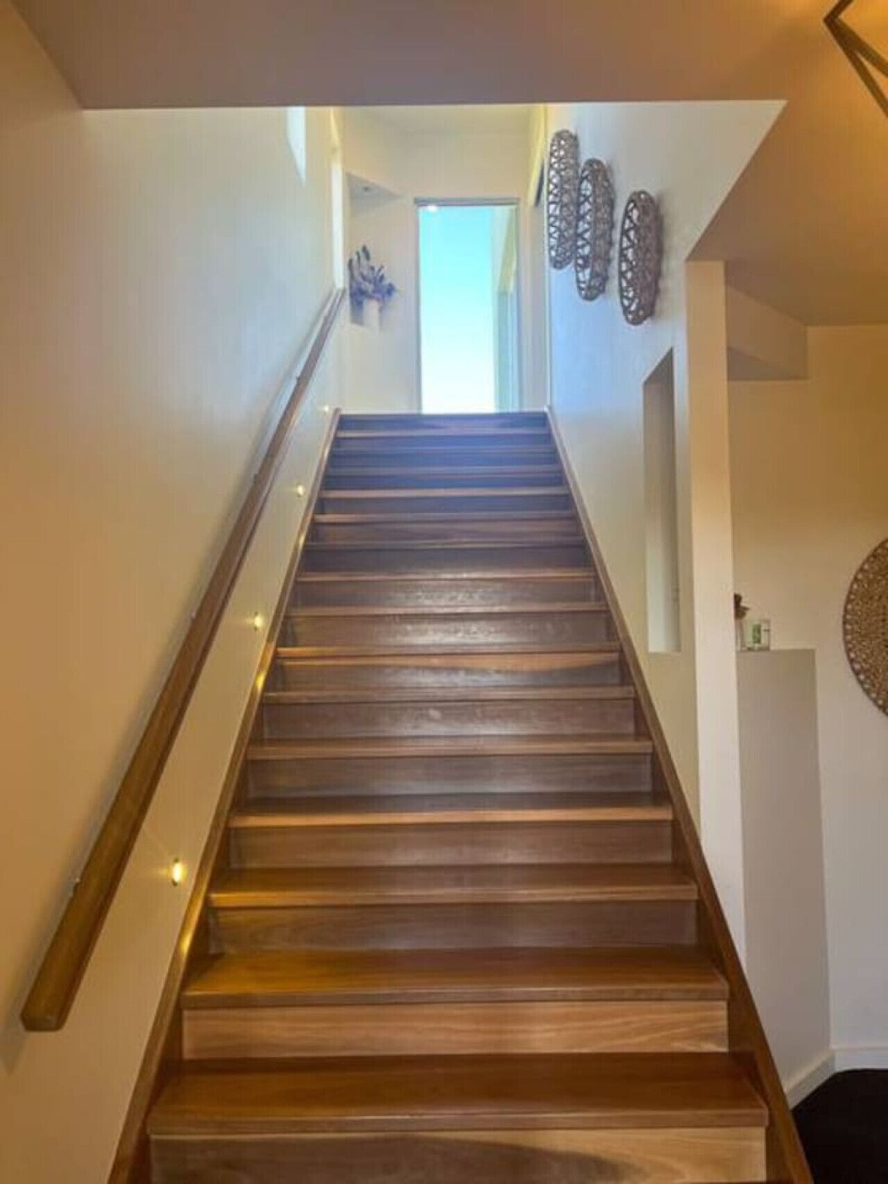 A wooden staircase with a handrail, leading to a door at the top.
