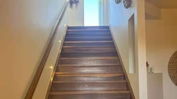 A wooden staircase with a handrail, leading to a door at the top.