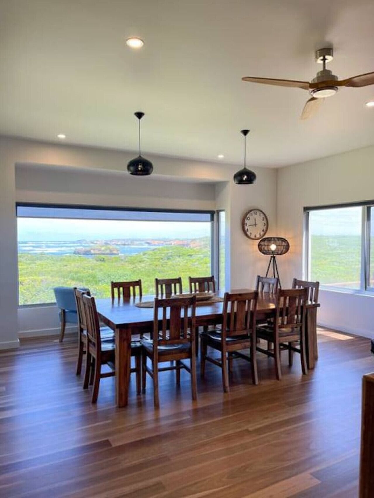 A dining area with a table and chairs, large windows with a view, ceiling fans, and recessed lighting.