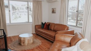 A living room with a brown leather sofa, a round wooden coffee table, and a ceiling fan.