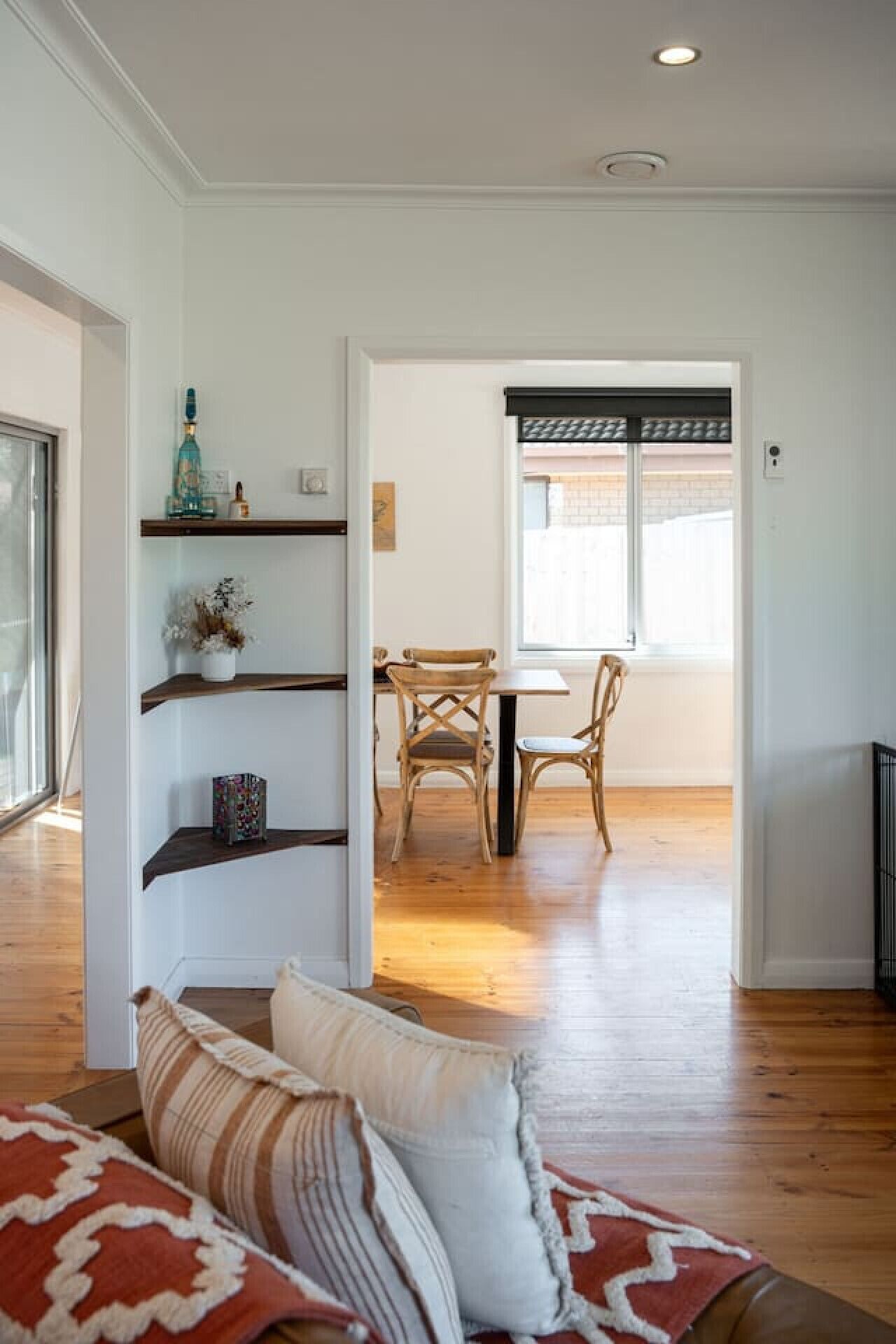 A living room with a sofa, a dining area with a table and chairs, and a hallway leading to a kitchen.