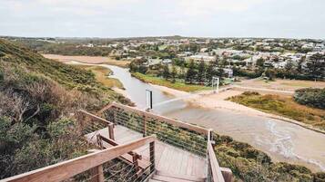 A wooden staircase leading down to a river with a view of a town in the distance.