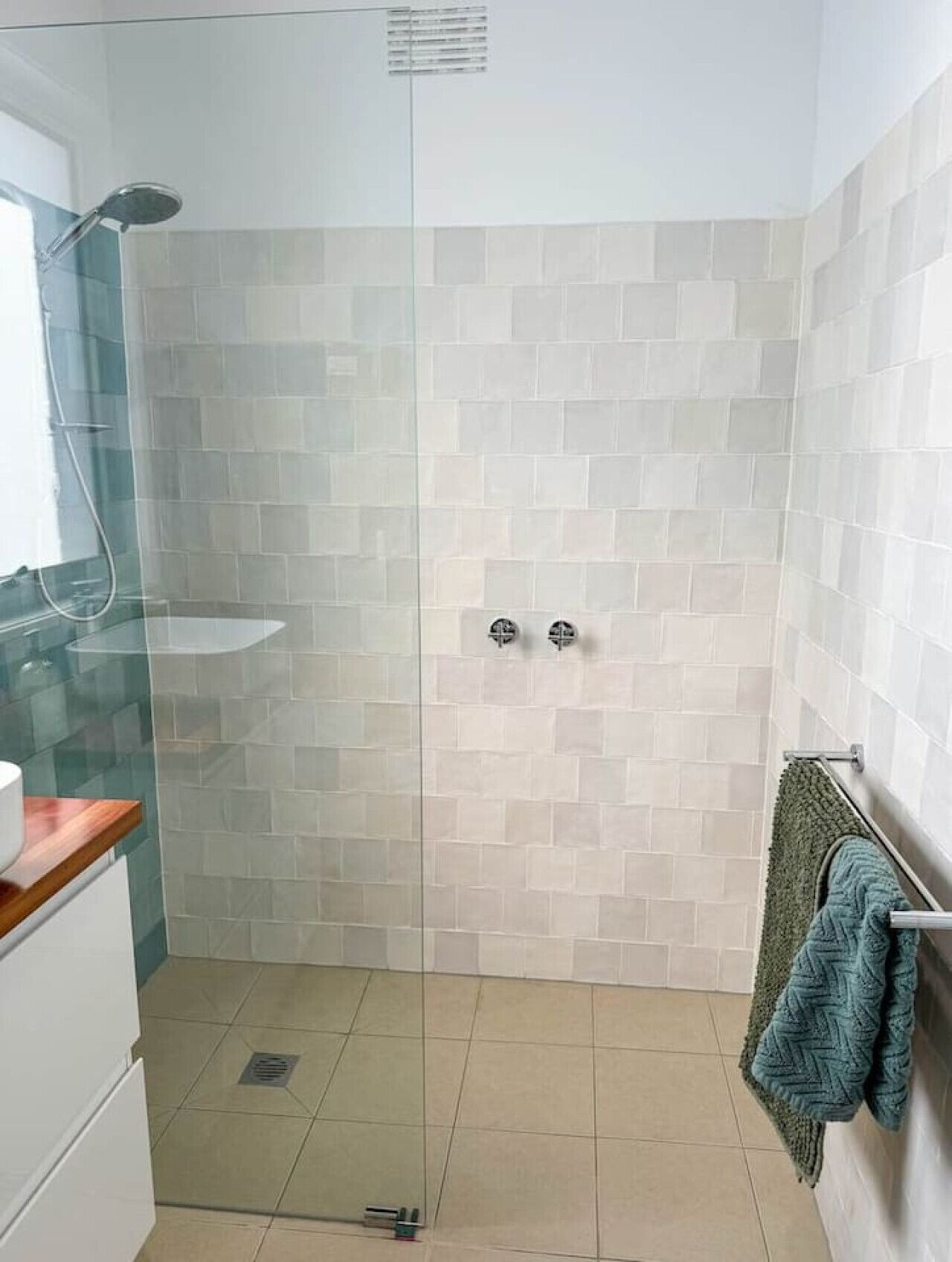 Eine Dusche mit Glastür, ein Waschbecken und ein Handtuchhalter.