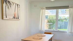 A dining area with a table and chairs, a ceiling fan, a window with curtains, and a painting on the wall. - Campbell Cottage Port Fairy (Port Fairy)