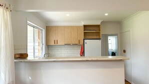 A modern kitchen with white cabinetry, a built-in oven, and a countertop. - Campbell Cottage Port Fairy (Port Fairy)