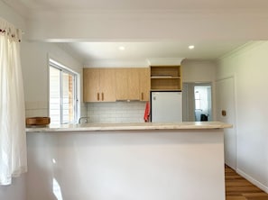 A modern kitchen with white cabinetry, a built-in oven, and a countertop. - Campbell Cottage Port Fairy (Port Fairy)