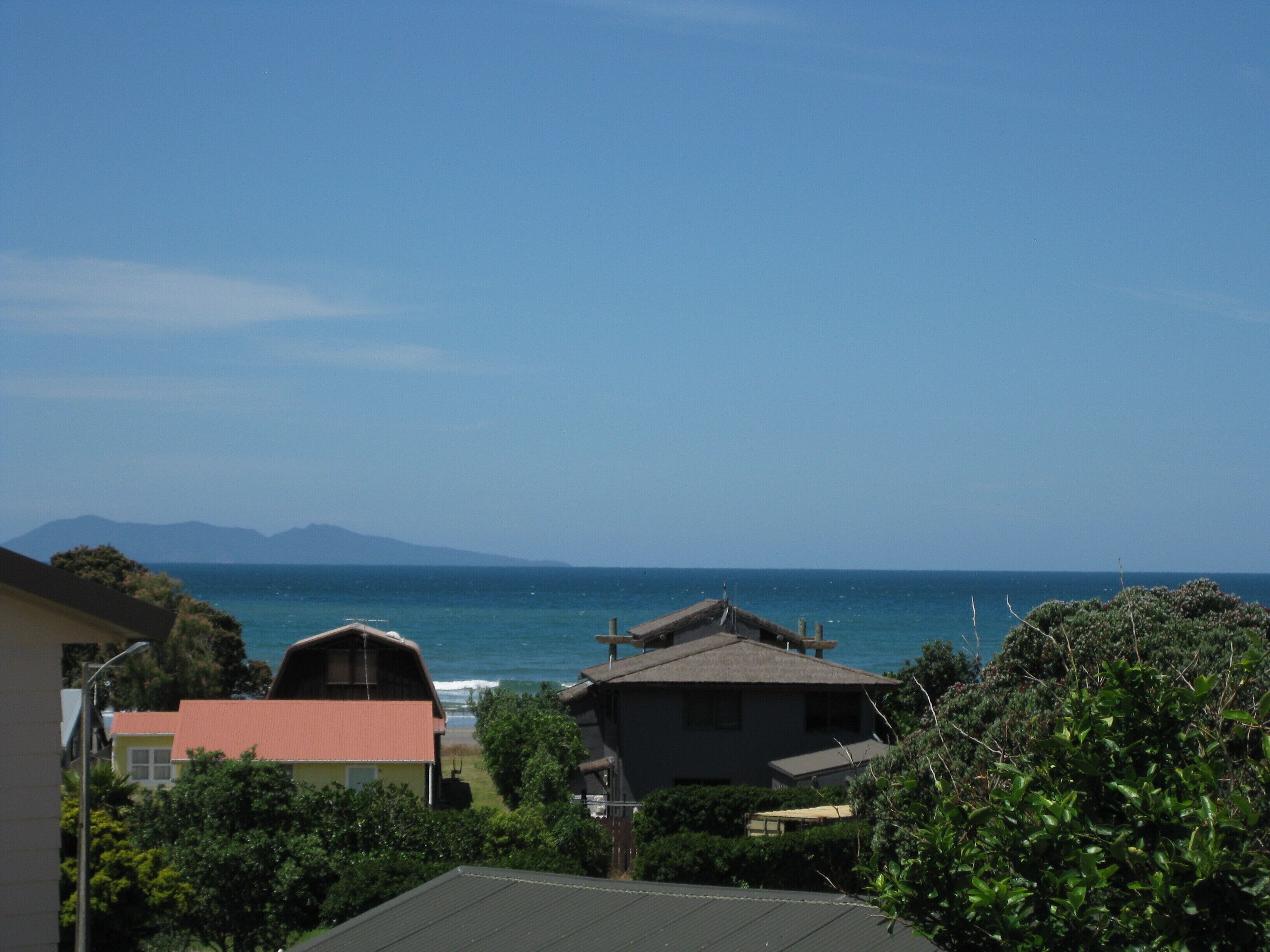 Un área residencial costera con casas, cielo despejado y vista al mar.