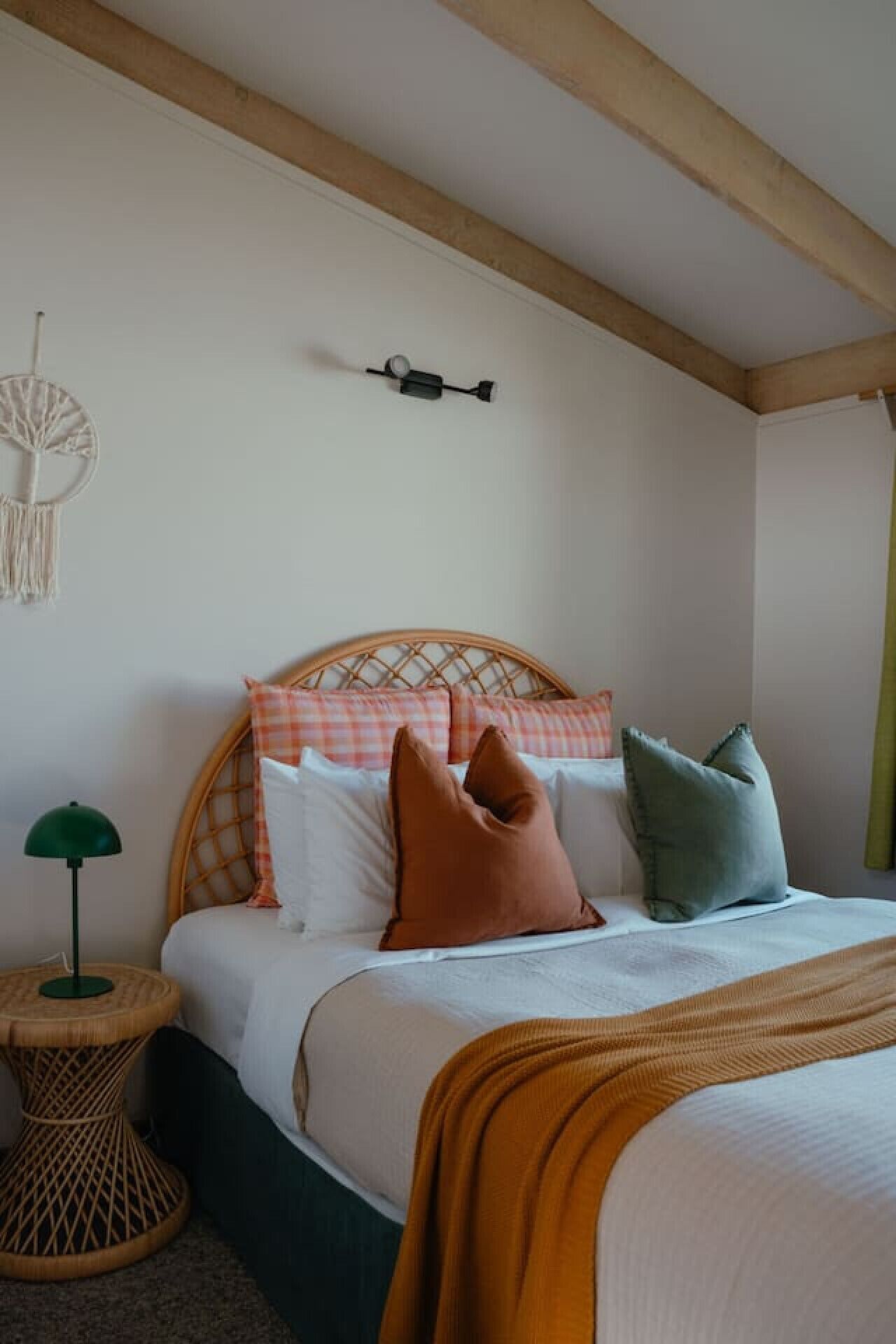 A bedroom with a bed, pillows, a wall-mounted light fixture, and a decorative wall hanging.