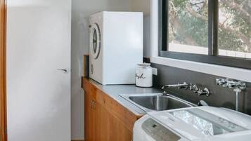 A compact kitchen with a washing machine, a sink, and a window providing natural light.
