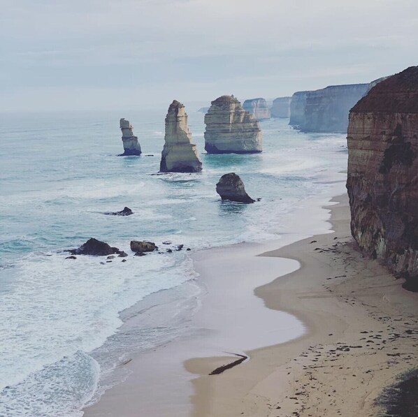 A coastal landscape with prominent rock formations and a sandy beach.