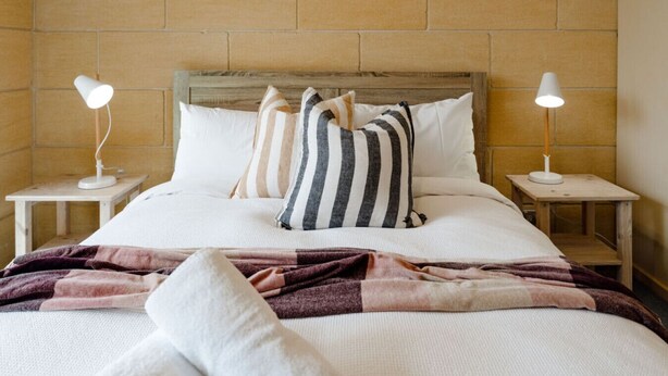 A bed with a wooden headboard, two bedside lamps, and striped pillows.