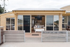 A modern house with a covered porch, a sliding glass door leading to a living area with a sofa and a coffee table.