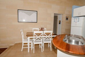 A small kitchenette with a sink, a white refrigerator, and a wooden countertop.