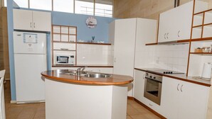 A compact kitchen with a central island, a microwave, a stove, and a refrigerator.
