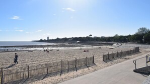 A beach with a wooden fence, a concrete walkway, and a clear sky. - Charmante maisonnette (La Rochelle)