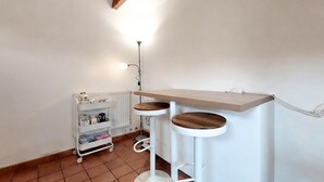 A corner of a room with a white radiator, a white shelf unit, and a white floor lamp. - Charmante maisonnette (La Rochelle)