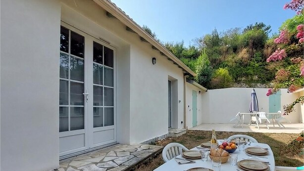 A patio with a table set for dining, a bottle, and fruit. - Beautiful home in Royan with WiFi (Royan)