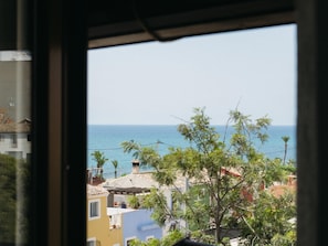 A coastal view through a window with buildings and a clear sky. - Albariño Harbor's Light (La Vila Joiosa)