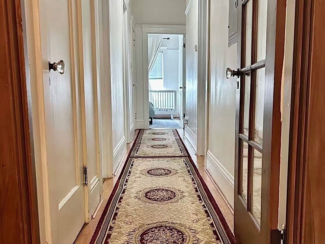 Un couloir avec un tapis à motifs menant à un balcon.