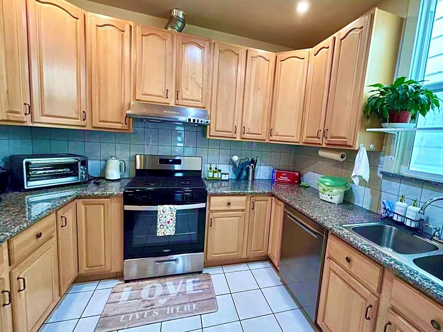 A kitchen with wooden cabinets, a stove, a sink, and a toaster.