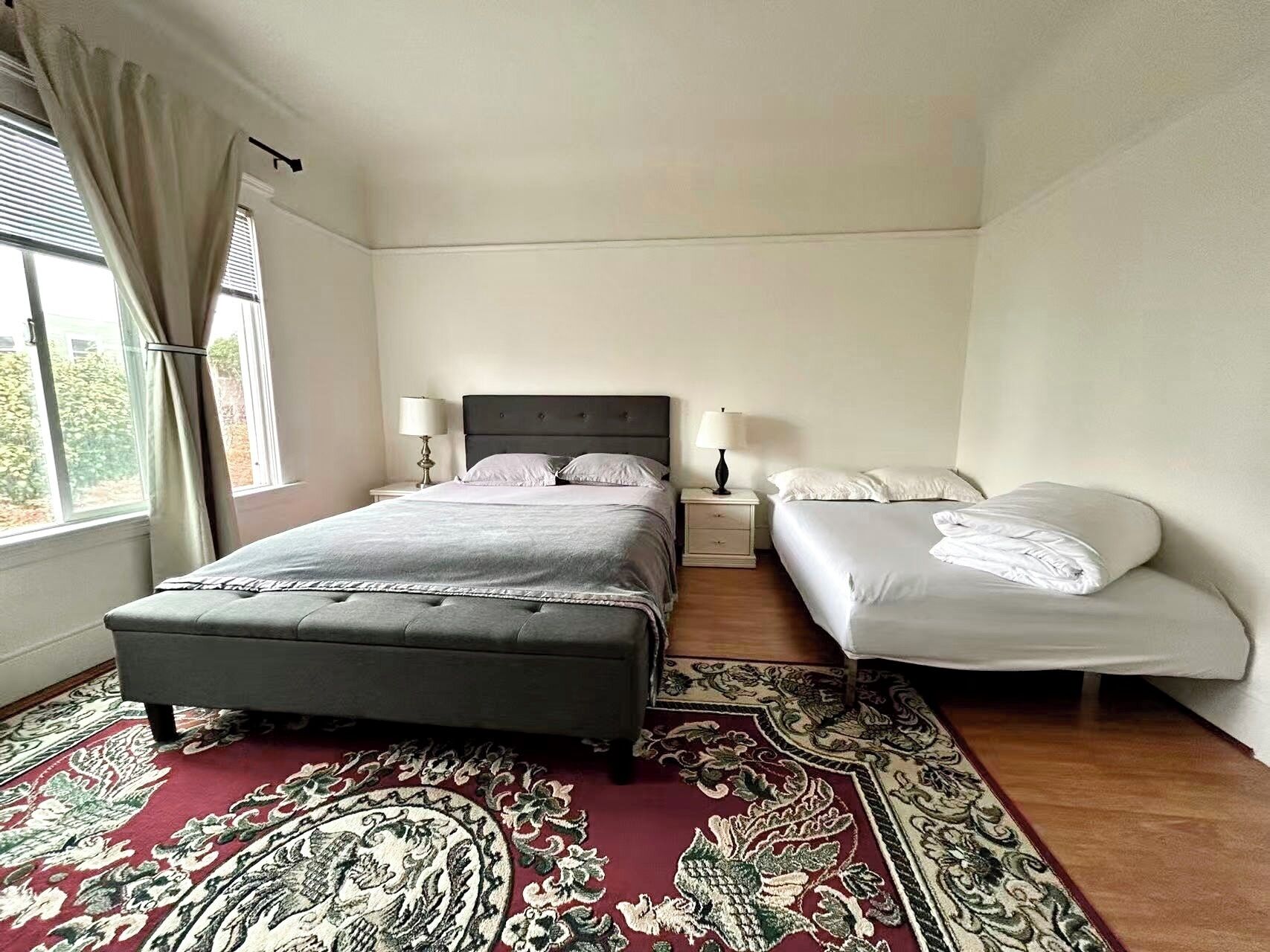 Ein Schlafzimmer mit einem großen Bett, zwei Nachttischen und einem gemusterten Teppich.