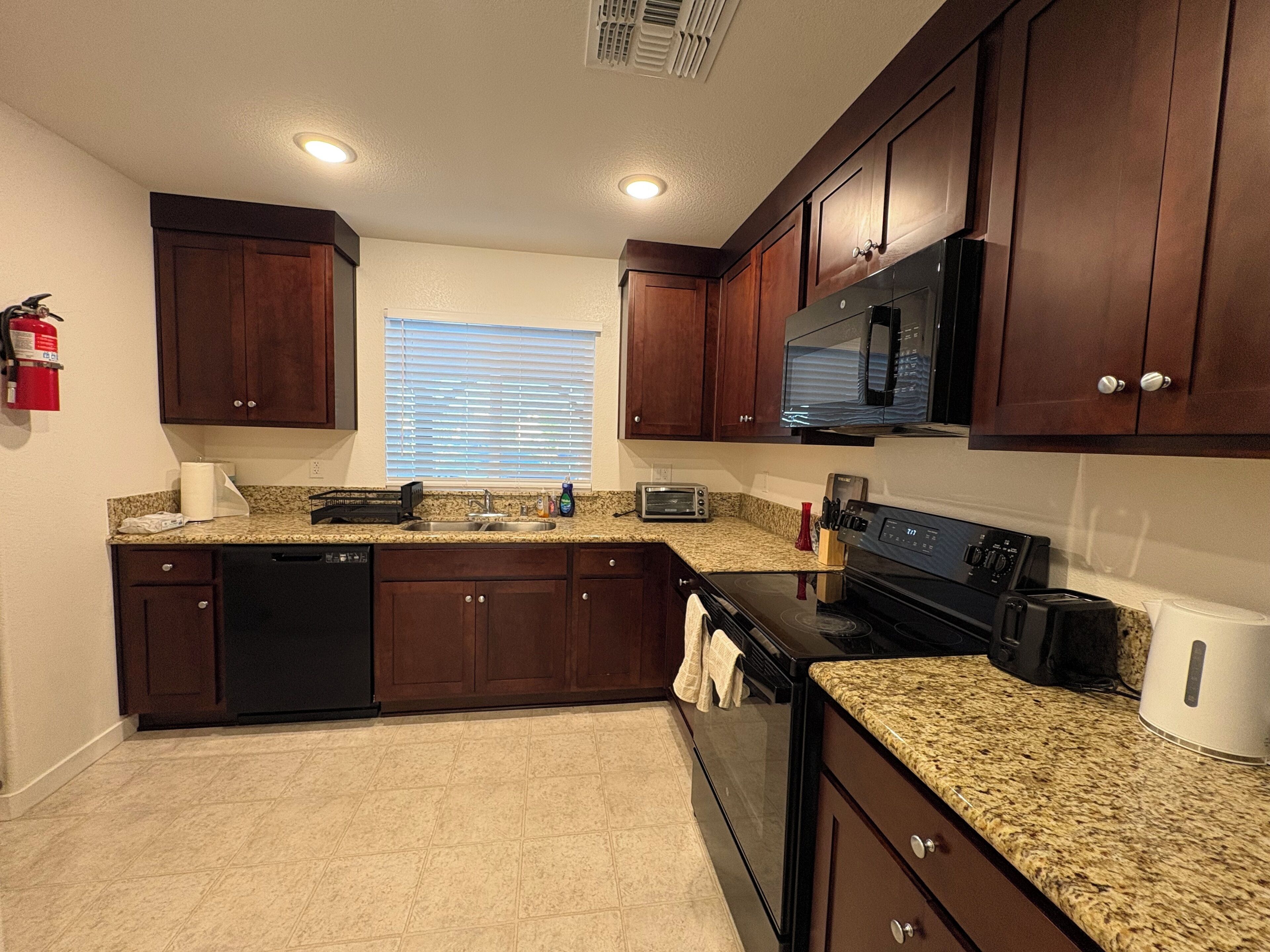 A kitchen with dark wooden cabinets, a stainless steel microwave, a built-in oven, and granite countertops.