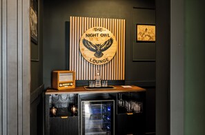 En bardisk med en träskylt där det står ”The Night Owl Lounge”, en gammal radio och ett cocktailglas på disken.