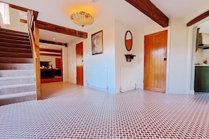 Un hall d’entrée spacieux, doté d’un sol à motifs, de portes en bois et d’un escalier.