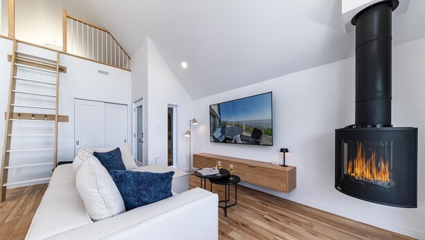 A modern living room with a white sofa, a black fireplace, and a wooden floor.