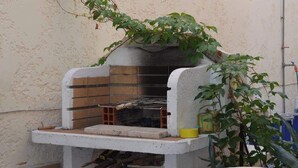 Un coin cuisine avec un four en briques, un plan de travail blanc et une plante en pot.