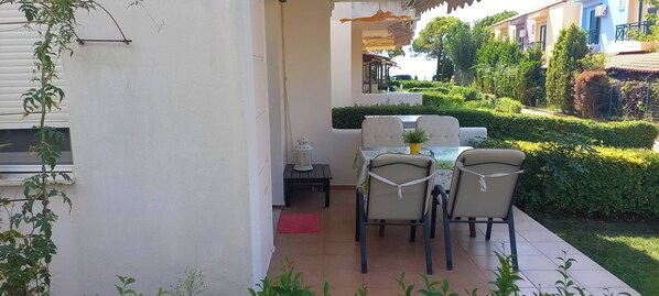 An outdoor patio with a table and chairs, a small table with a lantern, and a red mat. - Sea View Paradise Retreat in Nikiti (Nikiti)