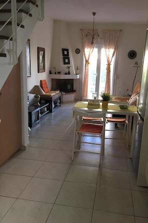 Ein geräumiger Wohnbereich mit Esstisch, Stühlen, einer Couch und einem Kamin.