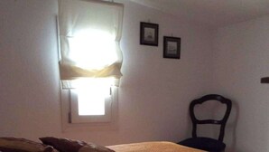 Une chambre à coucher avec un lit, une chaise et une fenêtre avec des rideaux.