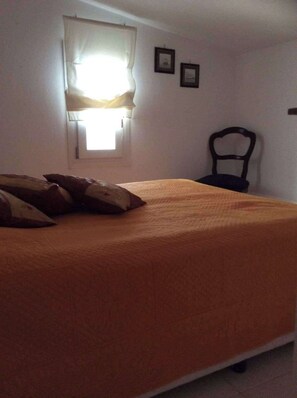 Ein Schlafzimmer mit einem Bett, einem Sessel und einem Fenster mit Vorhängen.