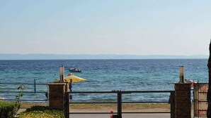 Une vue côtière avec un ciel dégagé, une étendue d’eau et une masse terrestre lointaine.