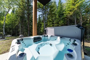 Ein Whirlpool mit einer hölzernen Überdachung, umgeben von bewaldetem Gelände.