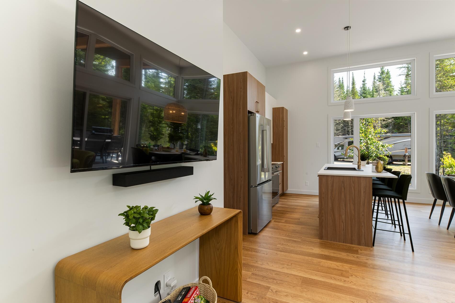 A modern kitchen with a built-in refrigerator, wooden cabinets, and a large window overlooking a garden.