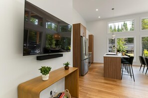 A modern kitchen with a built-in refrigerator, wooden cabinets, and a large window overlooking a garden.
