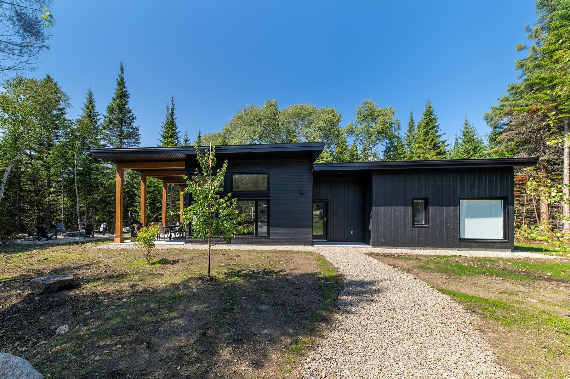 A modern two-story house with a covered patio area and a gravel driveway.