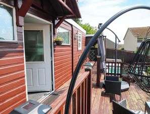 A wooden deck with outdoor seating, a pool, and a house with a white door.