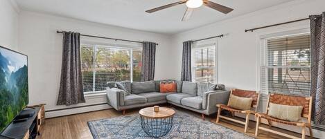 A living room with a sectional sofa, a coffee table, and a ceiling fan.