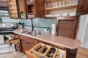 Una cocina con armarios de madera, un lavamanos doble y un especiero empotrado.