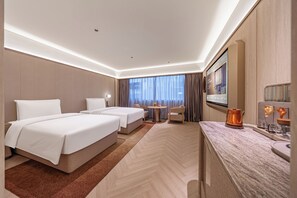 A hotel room with two beds, a sitting area, a small table, and a large mirror.