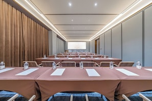 A conference room with rows of tables, chairs, and a projection screen.