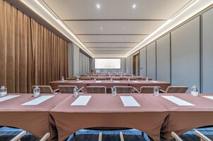A conference room with rows of tables, chairs, and a projection screen.