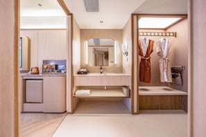 A modern bathroom with a sink, mirror, towel rack, and a small cabinet.