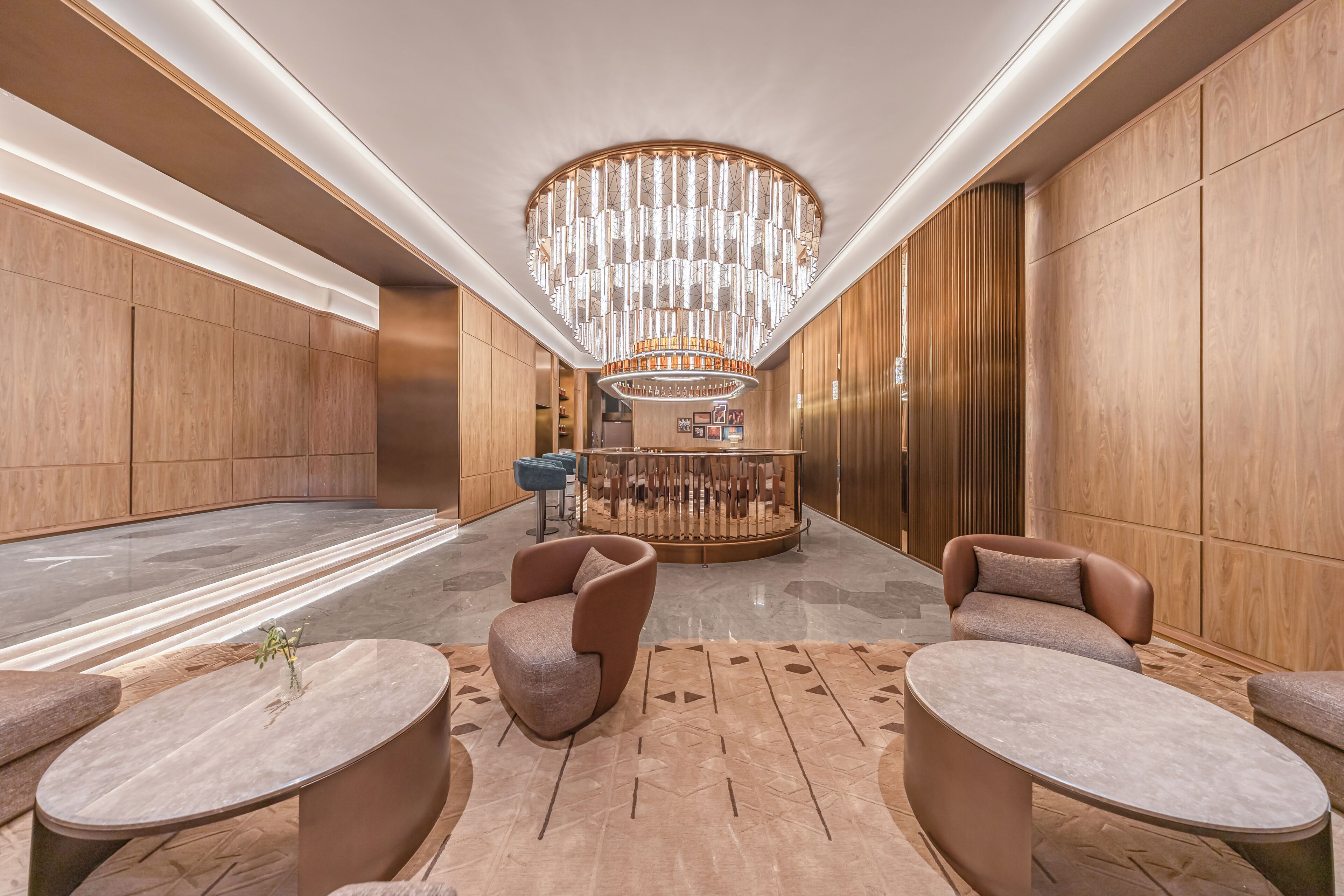 A lobby with a central bar area, seating arrangements, and a decorative ceiling light fixture.