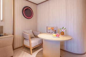 A modern room with a round table, a chair, a wall-mounted mirror, and a small painting. - Crystal Hotel Guiyang Penshuichi Baoshan (Guiyang)